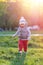 Toddler child in warm vest jacket outdoors. Baby boy at park during sunset.