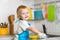 Toddler child washing dishes in kitchen. Little