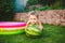 Toddler cute Caucasian white European race boy sitting hugging holding huge watermelon and smiling on background of green grass,