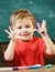 Toddler cute and cheerful ready to study. Kid boy in classroom near colorful markers, chalkboard on background, close up