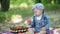 Toddler in denim suit and a cap holding apples in the hands