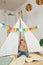 Toddler eating bread and butter in a hut with stay at home flag garland across