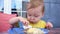 Toddler funny dips hands into saucy food and eats at table