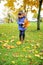 Toddler girl in blue coat picking up leaves