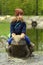 Toddler girl on a bronze frog statue traditional park decoration near lake