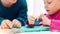 Toddler girl in child occupational therapy session doing sensory playful exercises with her therapist.