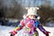 Toddler girl in colorful snowsuit plays in snow