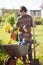 Toddler girl and her father harvesting carrot at the wheelbarrow, autumn day.