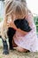 Toddler girl hugging and kissing a cute balck labrador retriever puppy