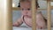 Toddler girl learning to keep her head lying in a crib.