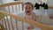 Toddler girl learning to keep her head lying in a crib.