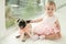 Toddler girl in a pink dress next to a pug puppy on the background of the view of the city close to panoramic windows