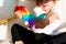 Toddler girl with popit toy in rainbow colours. Dino shape silicone toy for stress relief. Bubbles sensory trendy fidget