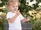 Toddler girl touches her nose with a finger covered in paint.