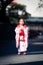 A toddler girl walking on the street wearing a red Japanese kimono.