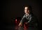 Toddler in gray boots and sparkling suit. She playing with three red balls, sitting on floor. Twilight, black background. Close up