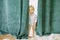 Toddler hides behind a curtain and looks out from it
