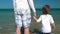 Toddler holding hands with his father at the sea shore