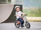 Toddler kid learning to ride on run bicycle at skate park.