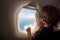 Toddler looks at the ground through the porthole of a flying plane