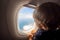 Toddler looks at the ground through the porthole of a flying plane