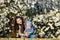 Toddler with mom on the background of flowering trees. little baby on hands of mother. woman playing with child outside in