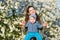 Toddler with mom on the background of flowering trees. little baby on hands of mother. woman playing with child outside in