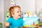 Toddler in party cap sit with birthday cake