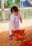 A toddler petting a chicken at a farm in Thailand