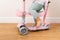 Toddler playing with scooter at home in the living room with teddy bear in basket