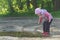 Toddler preschooler exploring summer puddle wearing red gums thin tree twig in hand