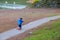 A toddler riding his pink scooter on a beach walkway