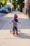 Toddler riding a tricycle down a sidewalk in a Chicago neighborhood