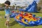 A toddler scratches his head while he stands next to a deflated bounce house