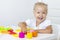 Toddler sculpts from colored plasticine on a white table.