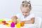 Toddler sculpts from colored plasticine on a white table