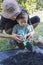 Toddler son and mother teaching little son preparing the soil to plant in a garden,