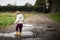 Toddler splashing in puddles in muddy country road