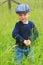 Toddler in tall grass wearing a flat cap.