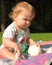 Toddler touching softball and looking at grass