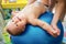 Toddler training with gymnastic ball with mother at home.