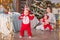 Toddler twins in red reindeer santa claus costumes take their first steps at home with their mother