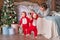 Toddler twins in red reindeer santa claus costumes take their first steps at home with their mother