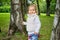 The toddler walks through the summer park among the trees