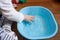 Toddlers hands in a blue basin on the floor