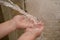 Toddlers hands playing in water from a guttering