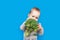 Todler with broccoli on blue background, healthy baby food. Complementary feeding of child with vegetables.