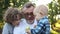 Todler eats an apple in the apple orchard with his grandfather and older brother. Grandfather tears apple root, happy