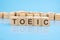 TOEIC - text of on wooden cubes, reflected from the bright blue surface