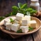 Tofu soy cheese or paneer or feta cheese cubes adding fresh parsley and celery in a ceramic bowl on a wooden background